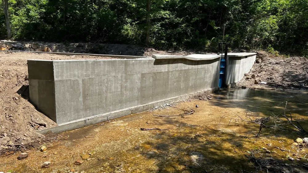A large concrete wall is next to a body of water.