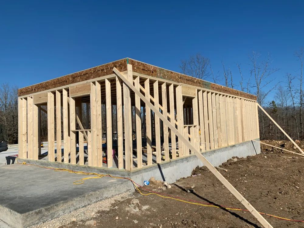 A wooden house is being built in the middle of a dirt field.