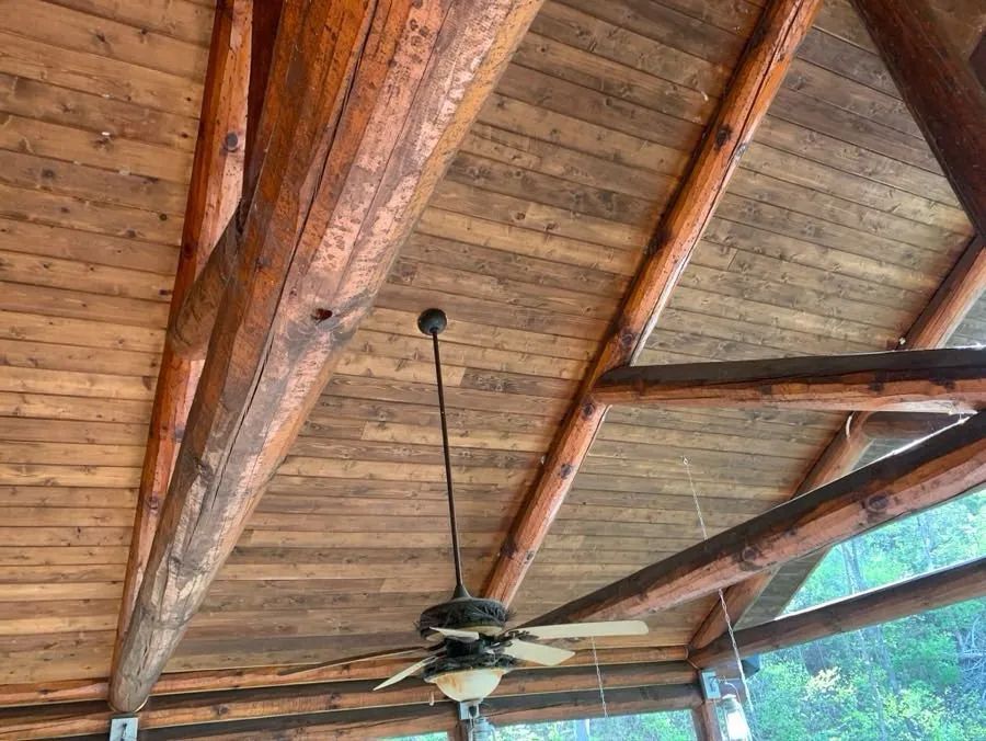 A ceiling fan is hanging from the ceiling of a wooden structure.