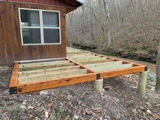 A wooden deck is being built in front of a wooden house.