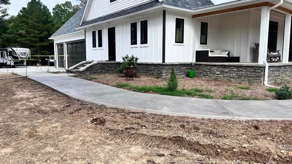 A white house with a concrete walkway leading to it.