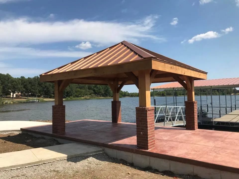 A gazebo is sitting on top of a dock next to a lake.