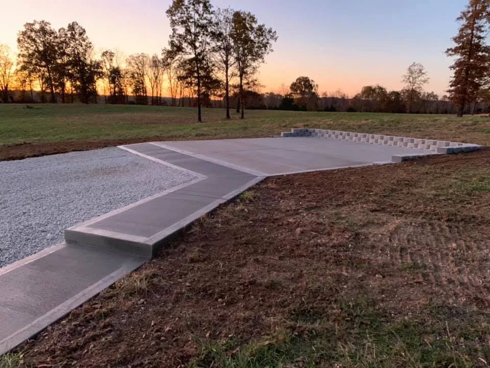 A concrete walkway going through a grassy field with trees in the background
