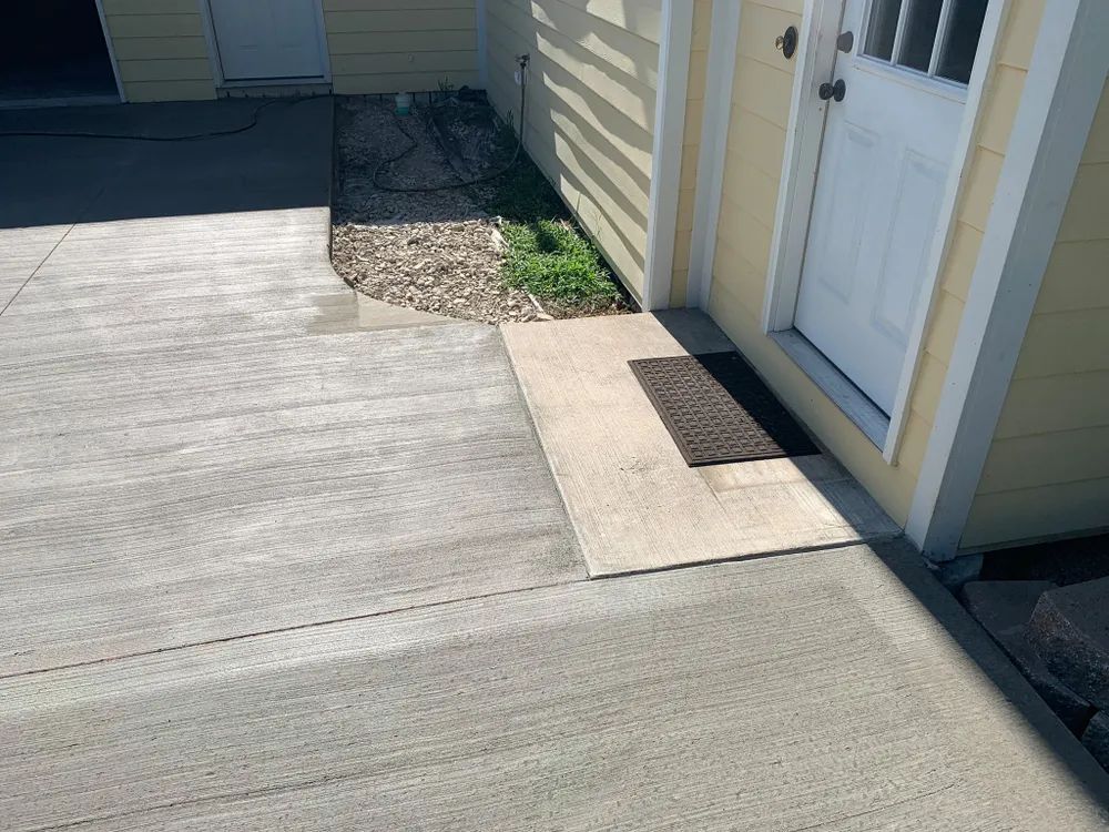 A concrete driveway next to a house with a white door.