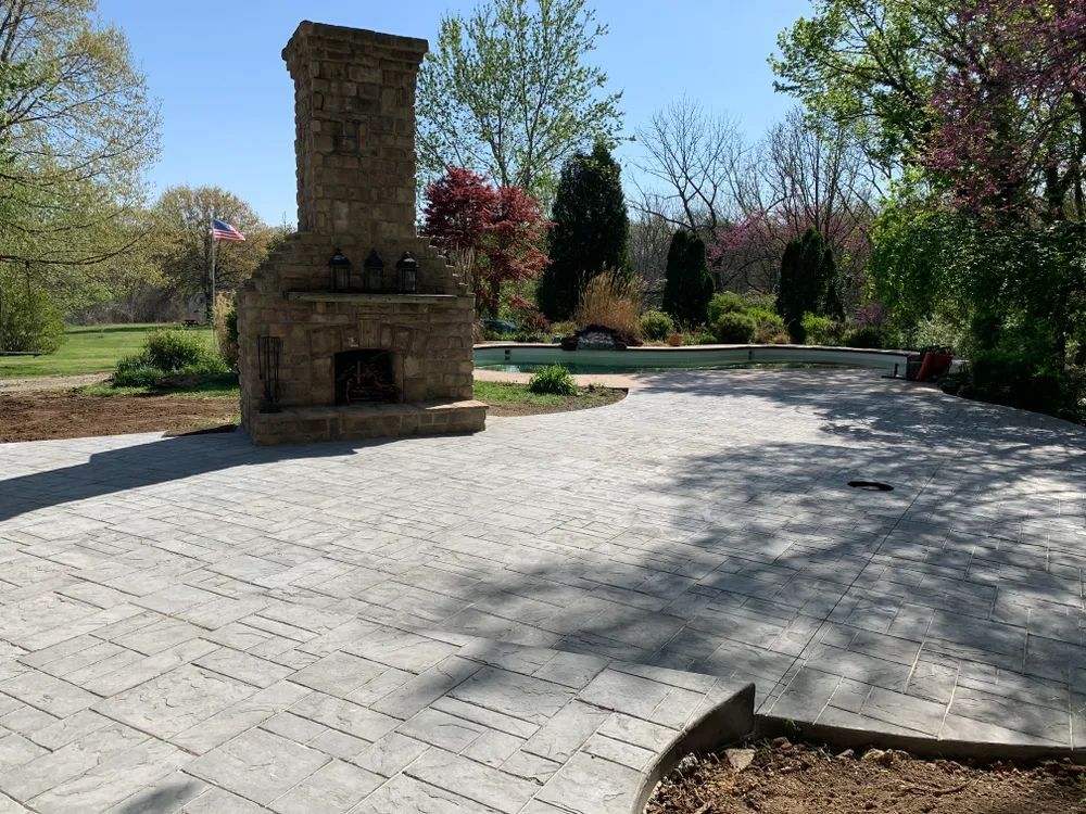 There is a stone fireplace in the middle of a patio.