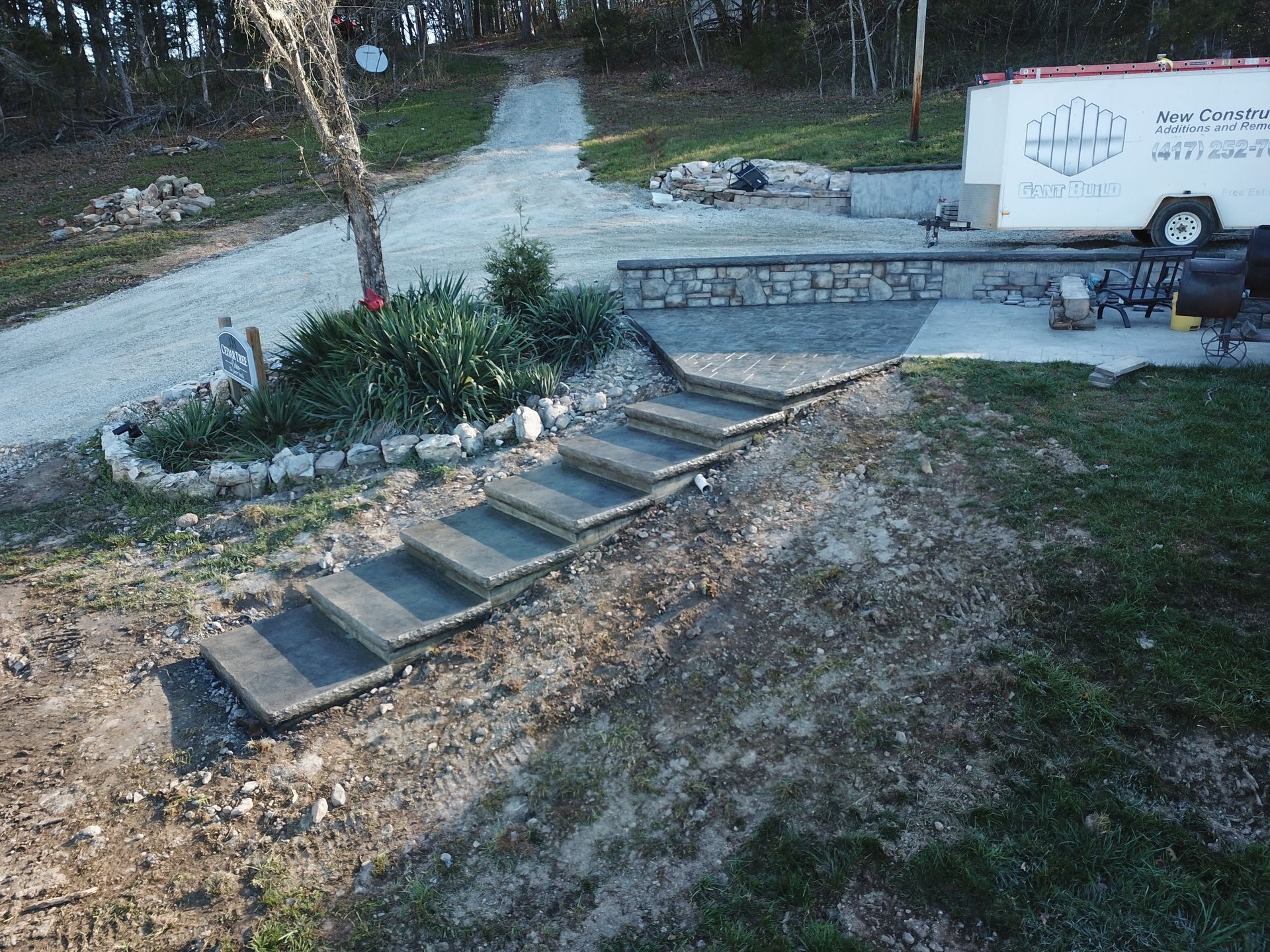 A white house with black garage doors and a concrete driveway in front of it.