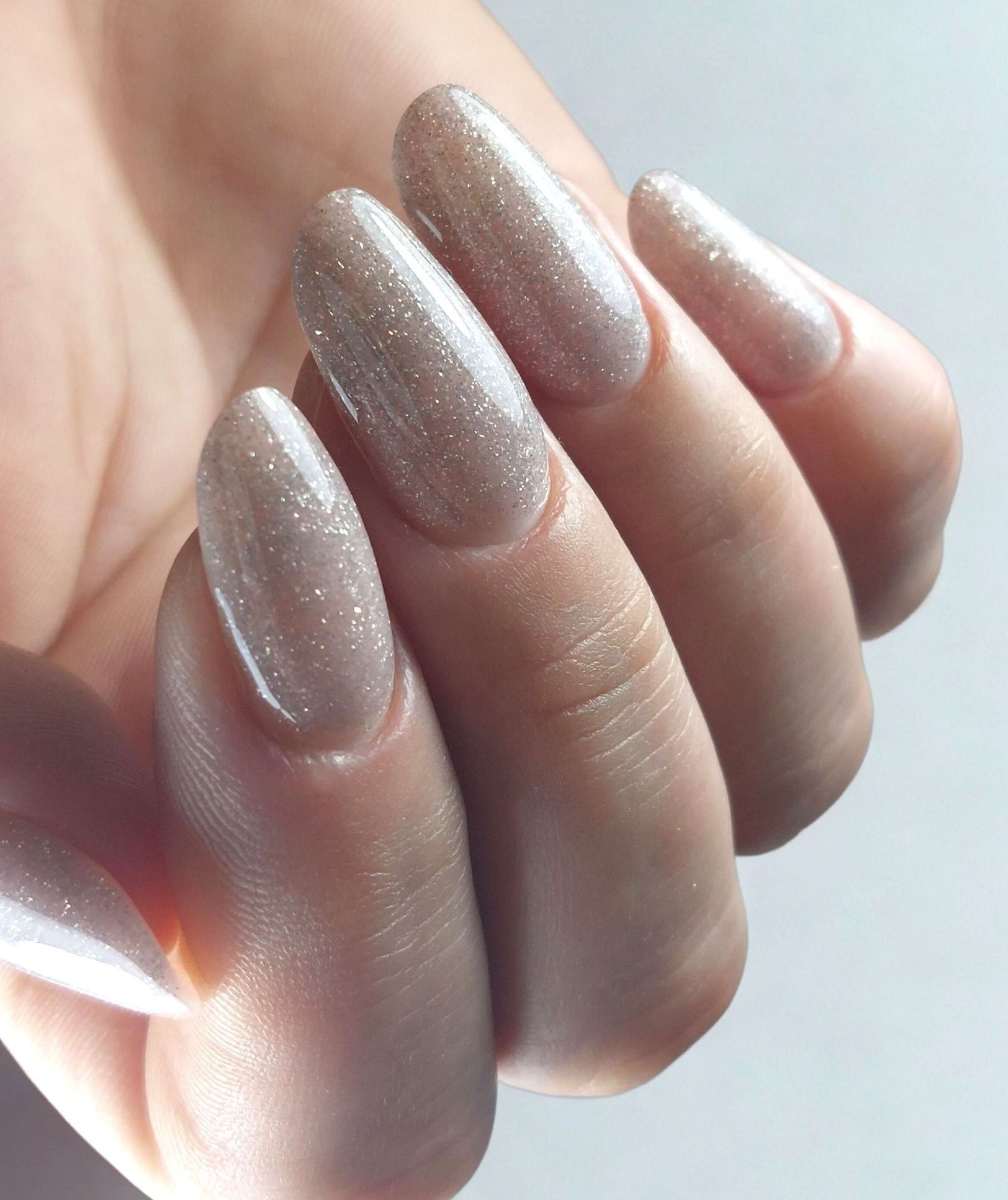 Een close-up van de hand van een vrouw met lange verlengde nagels met glitters