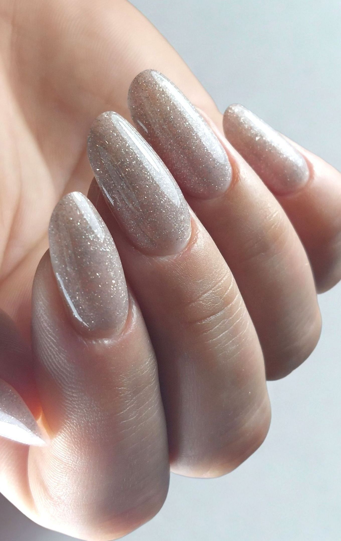 Een close-up van de hand van een vrouw met lange verlengde nagels met glitters