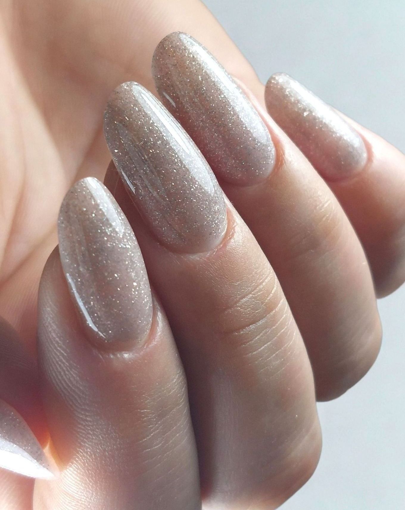 Een close-up van de hand van een vrouw met lange verlengde nagels met glitters