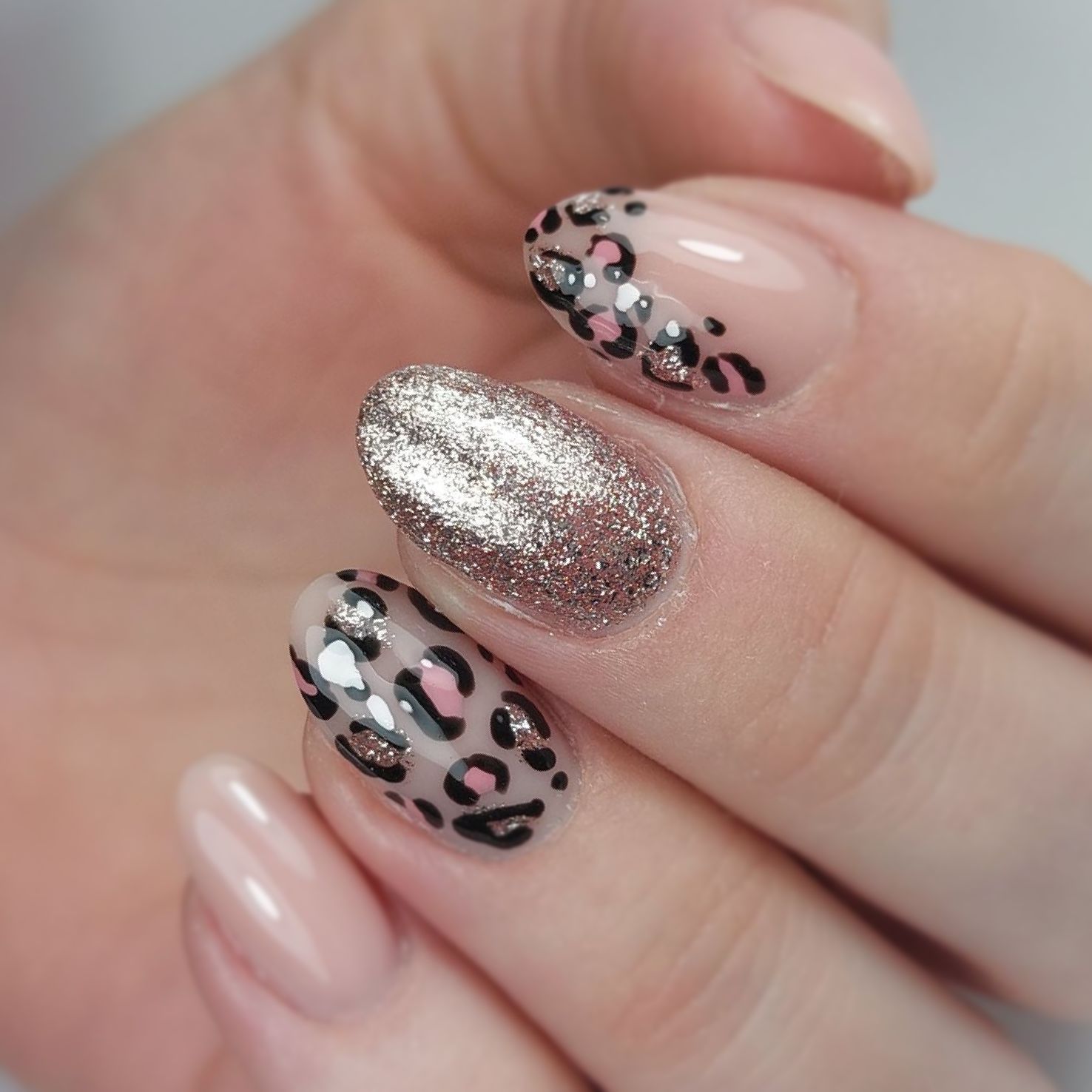 Een close-up van de nagels van een vrouw met een luipaardprintontwerp