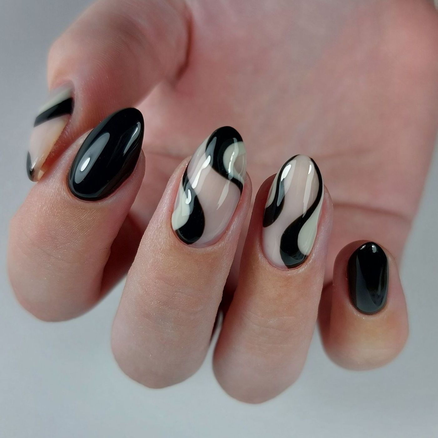 Een close-up van de nagels van een vrouw met zwart-witte swirl ontwerp