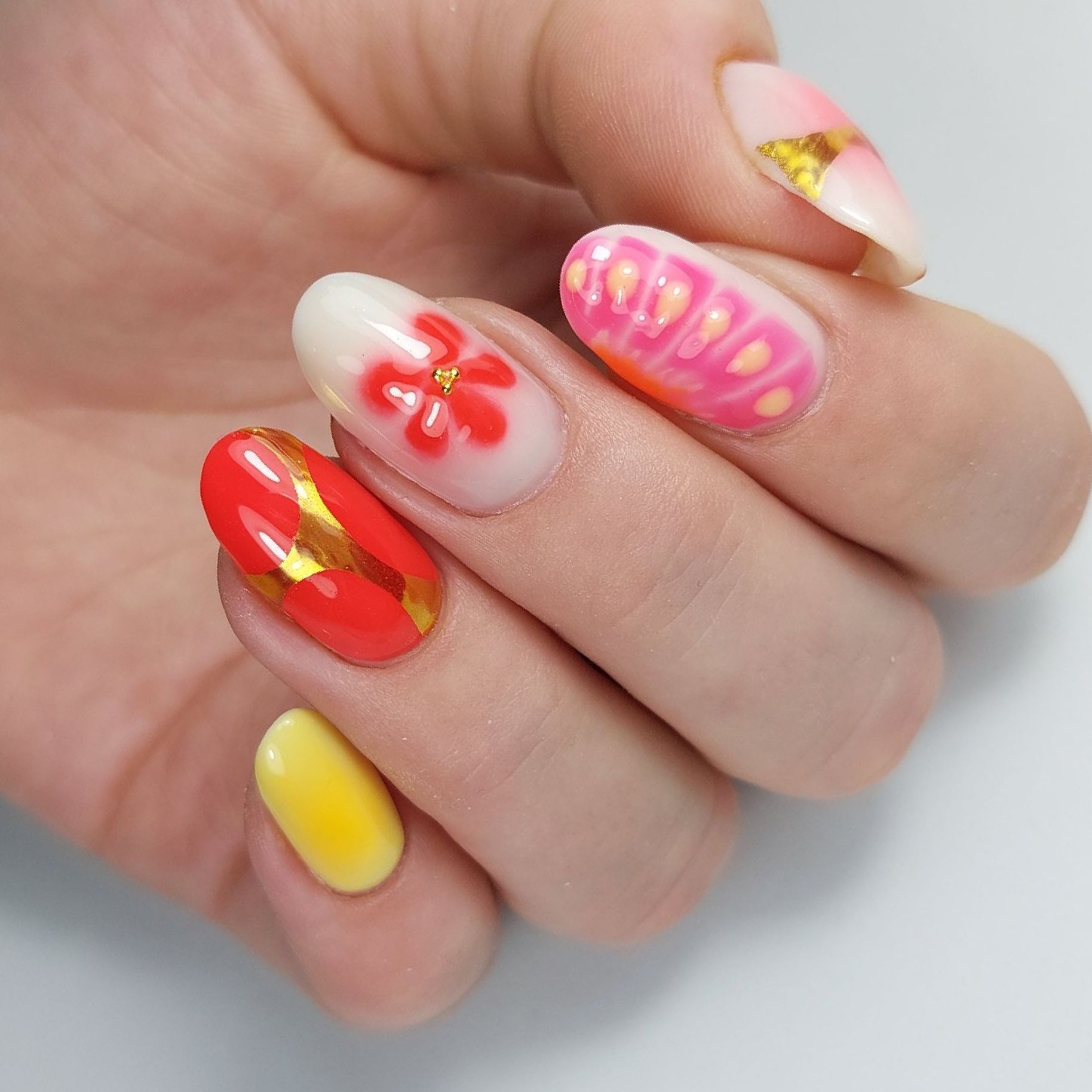 Close-up van hand met kleurrijke handgeschilderde bloem, met gouden lijnen Nailart Sint Annaparochie