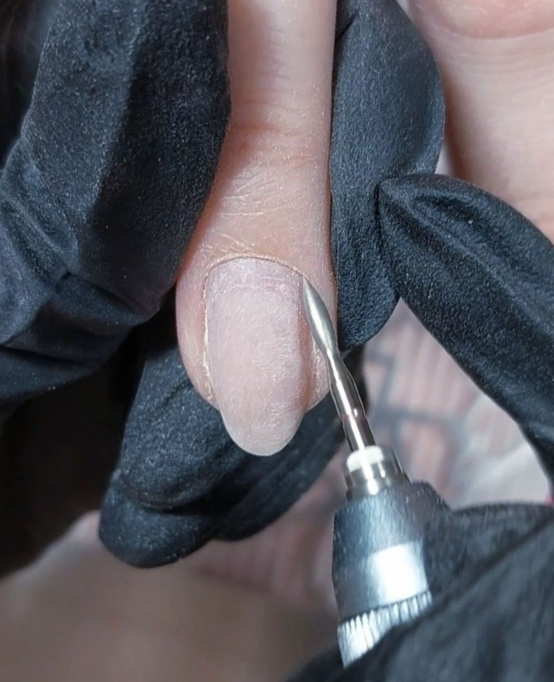 Close-up van een nagel waarbij zorgvuldig een veilige manicure wordt uitgevoerd.