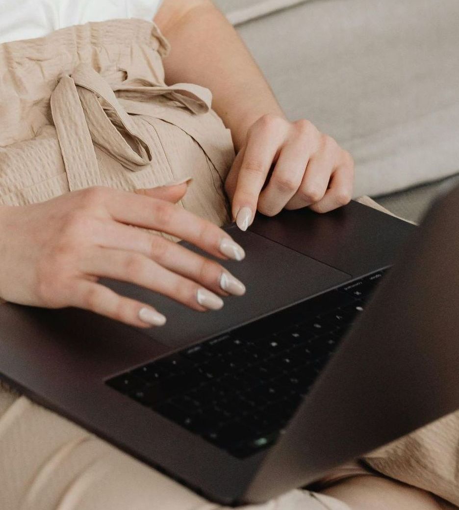 Een vrouw typt op een laptop.