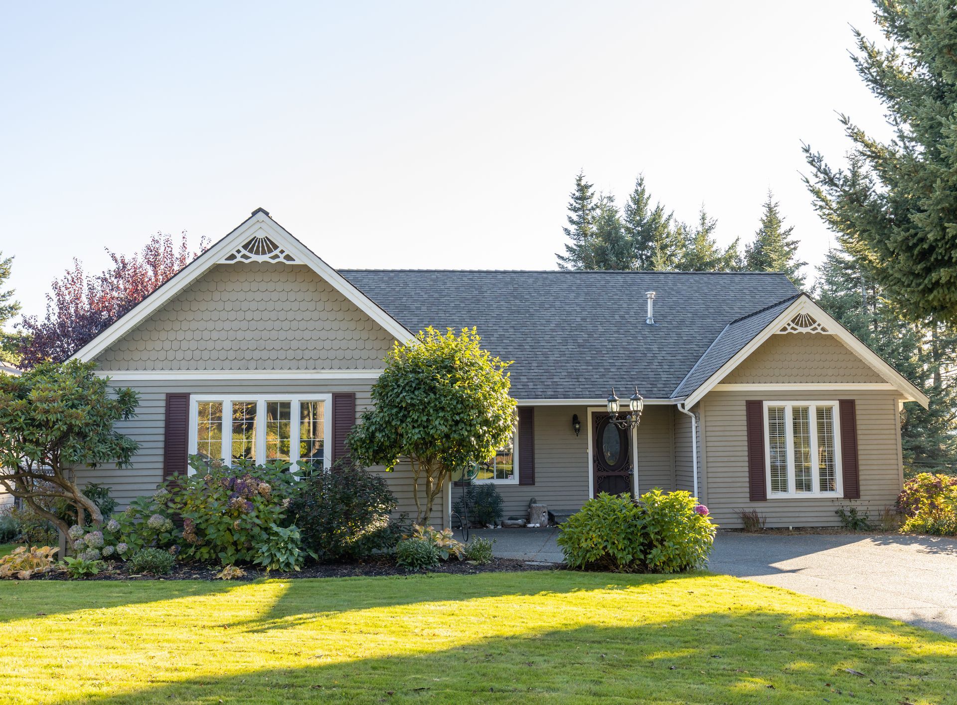 Large brick house with green lawn, blue sky, and trees.