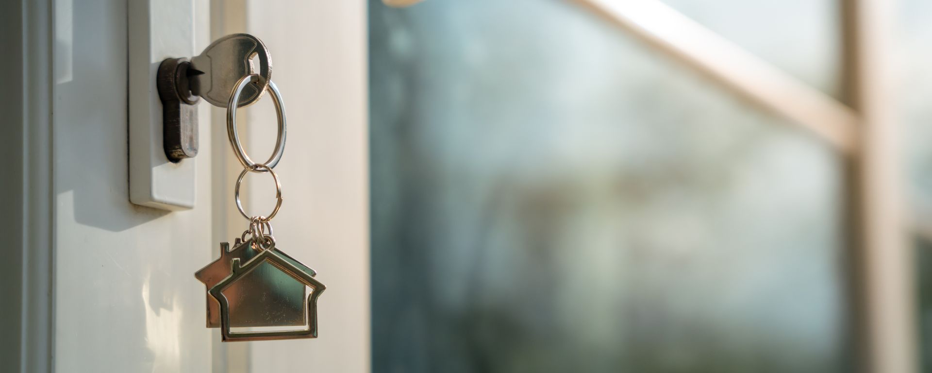 Key in a door, with a house-shaped keychain hanging down.