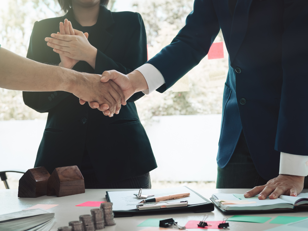 A group of business people are shaking hands over a table.