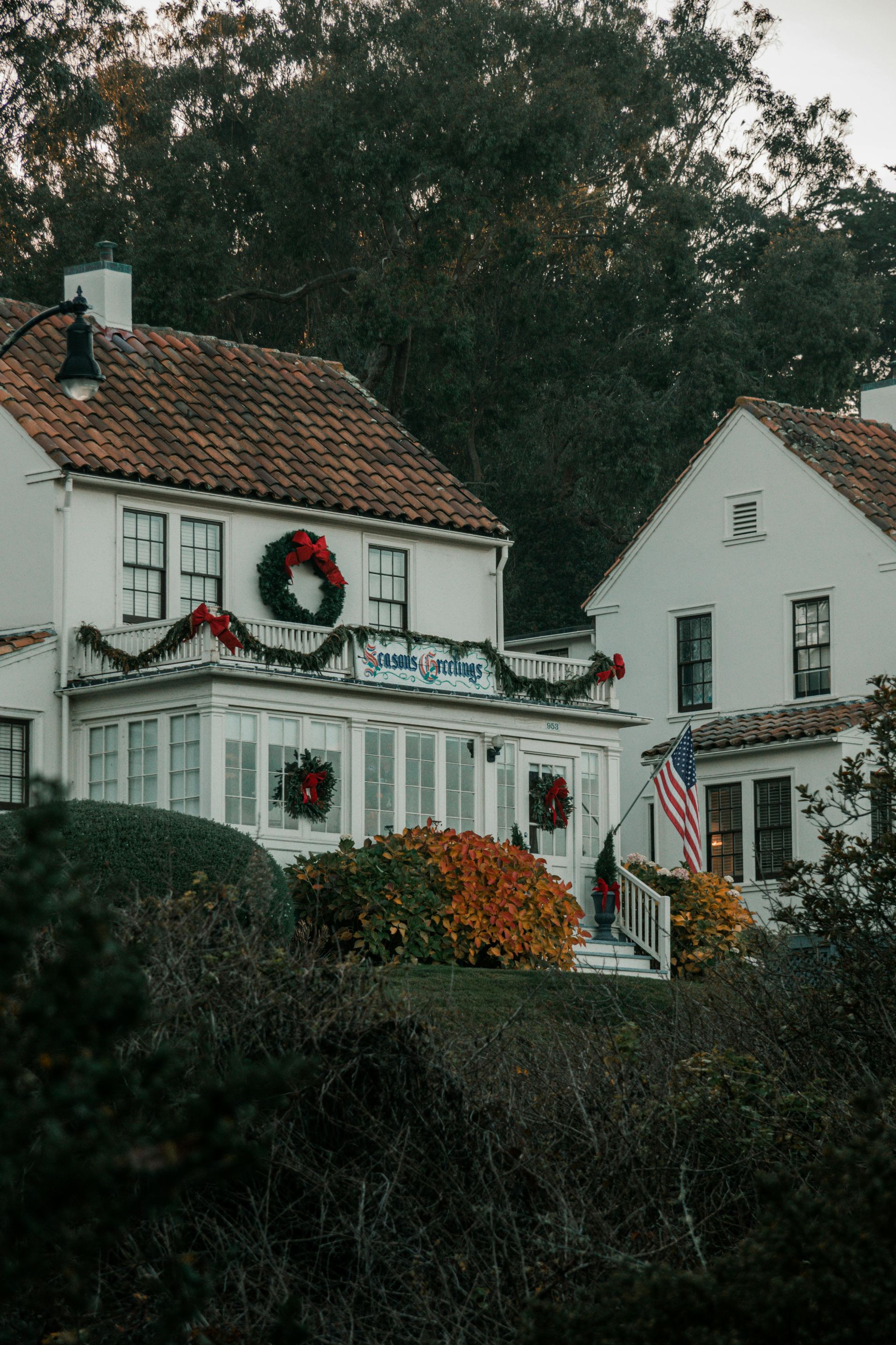 A white house decorated for christmas with a wreath on the front.