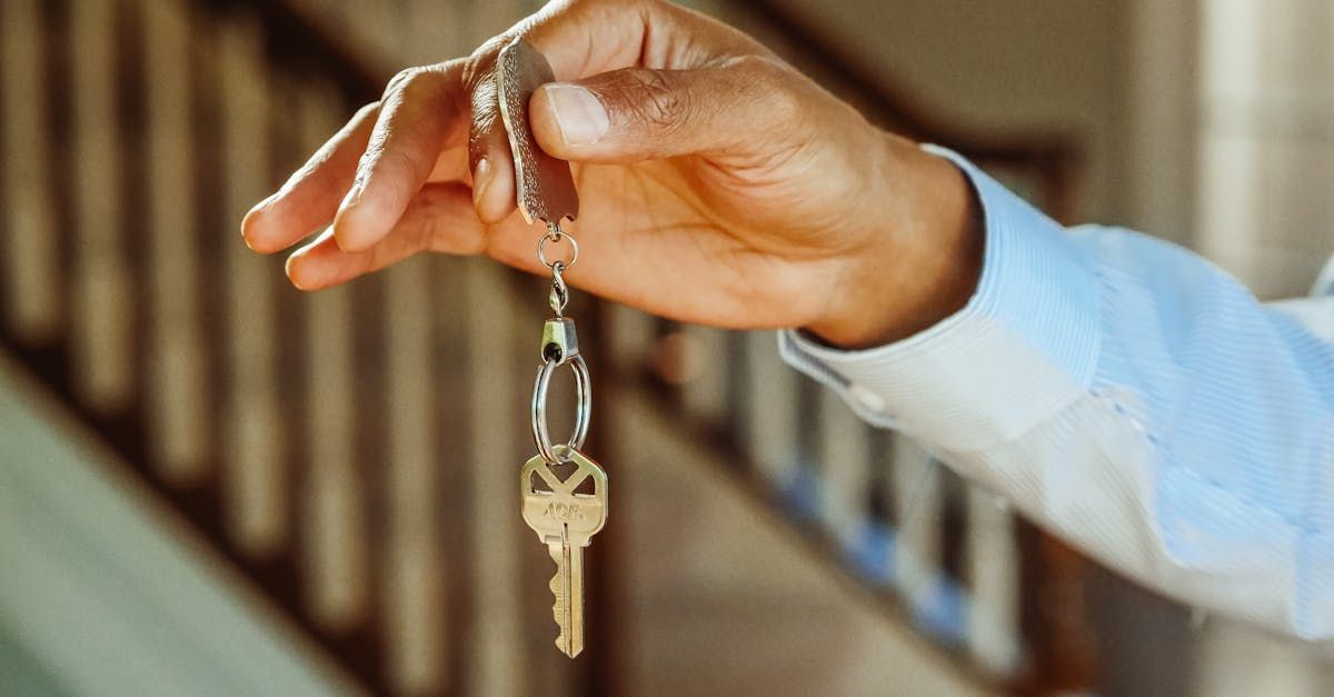 A person is holding a key in their hand in front of a staircase.