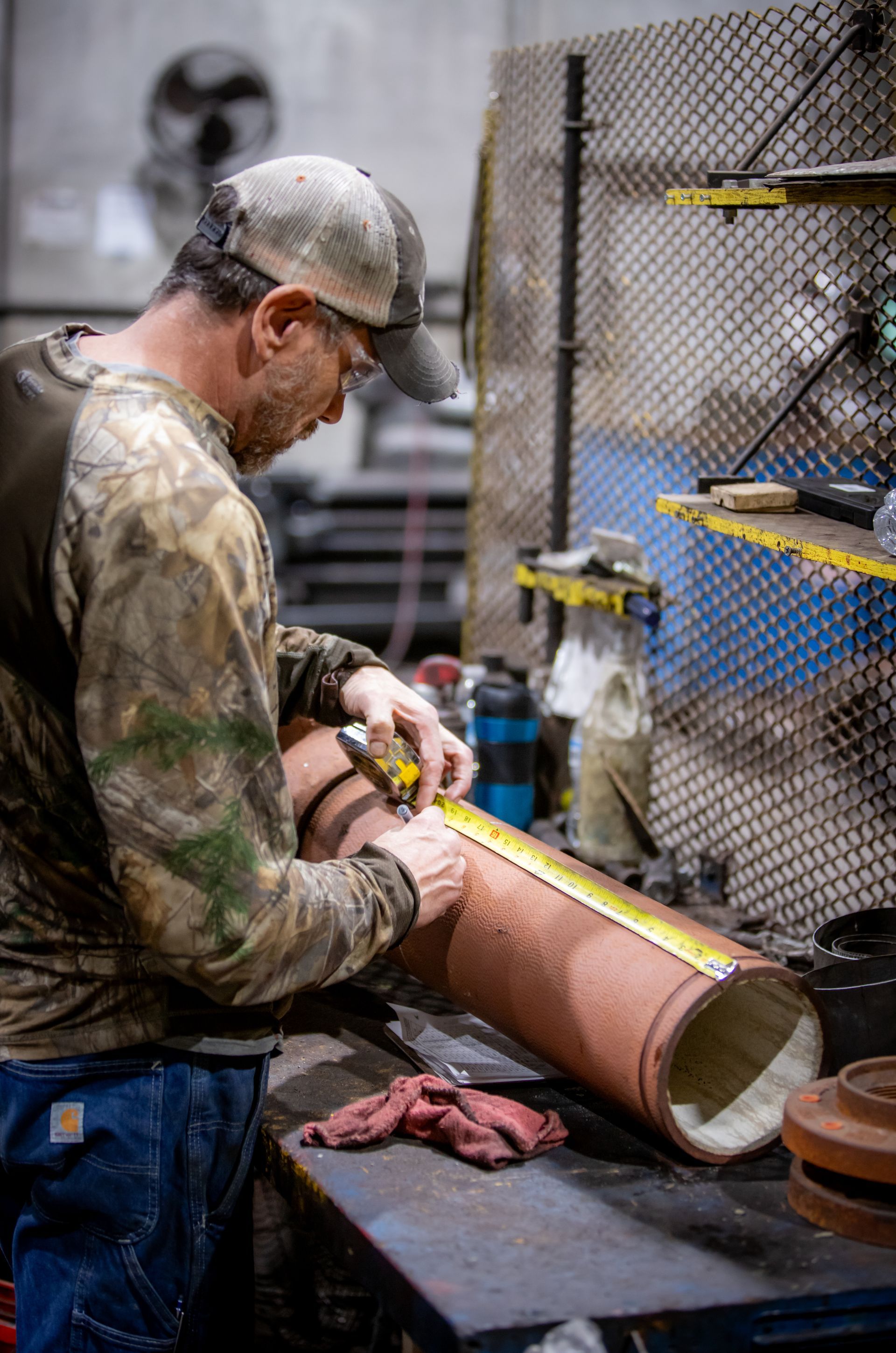 A man is measuring a pipe with a tape measure.