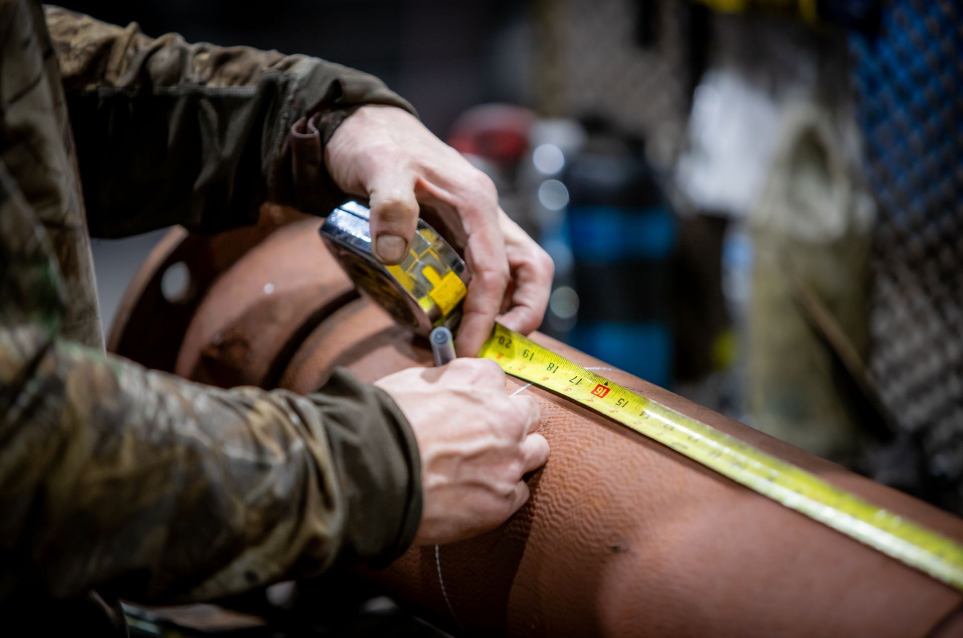 A man is measuring a pipe with a tape measure.