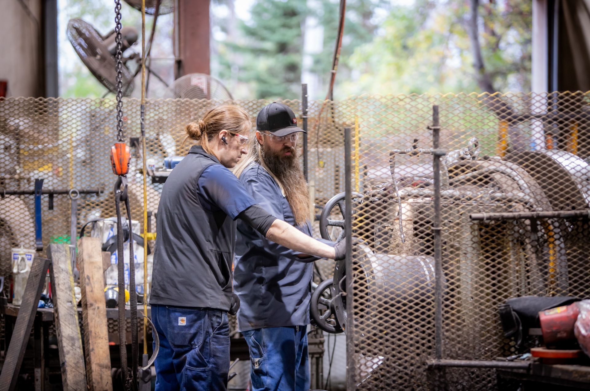 A man and a woman are working on a machine in a factory.