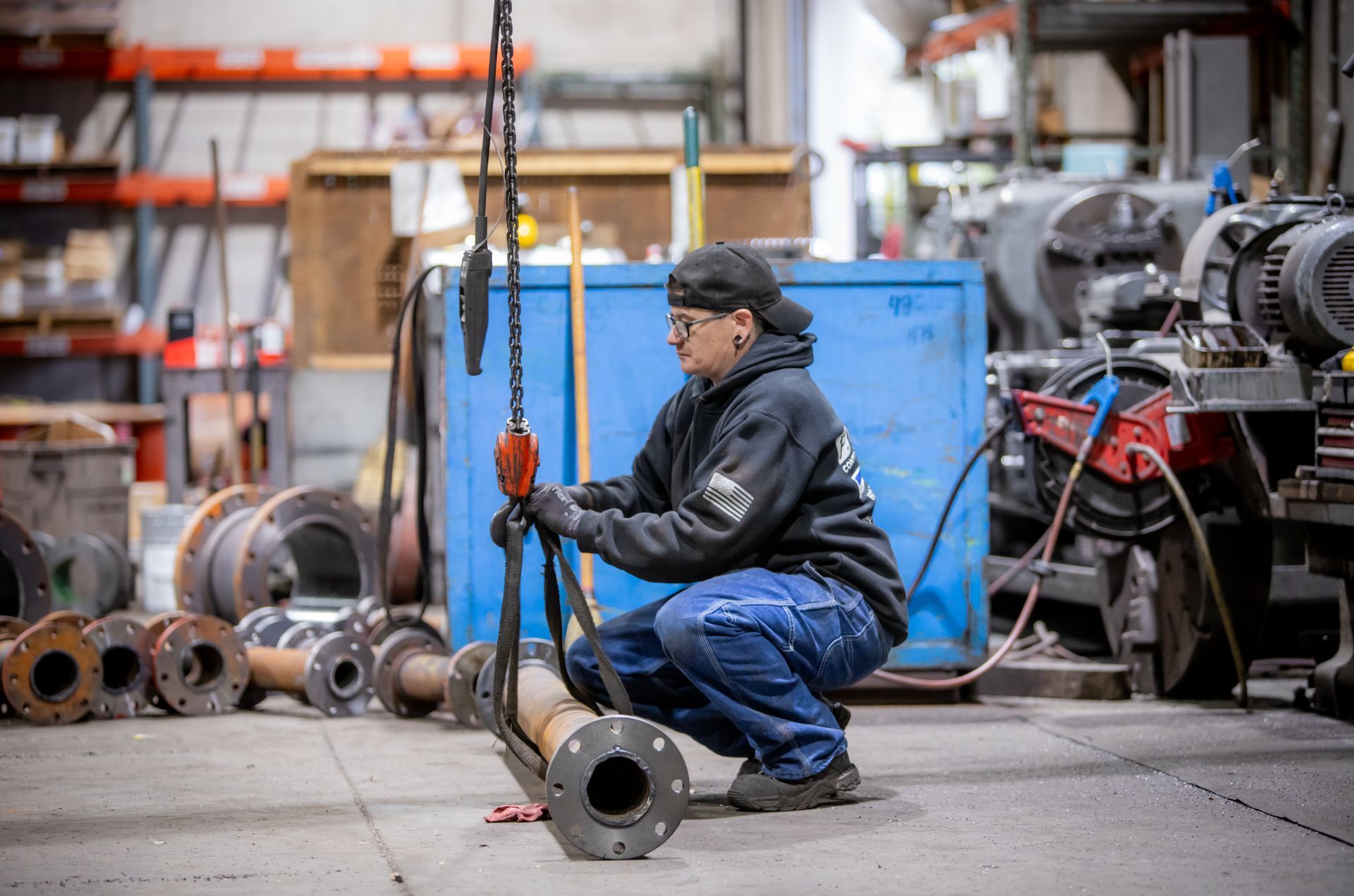 A man is kneeling down in a warehouse holding a crane.