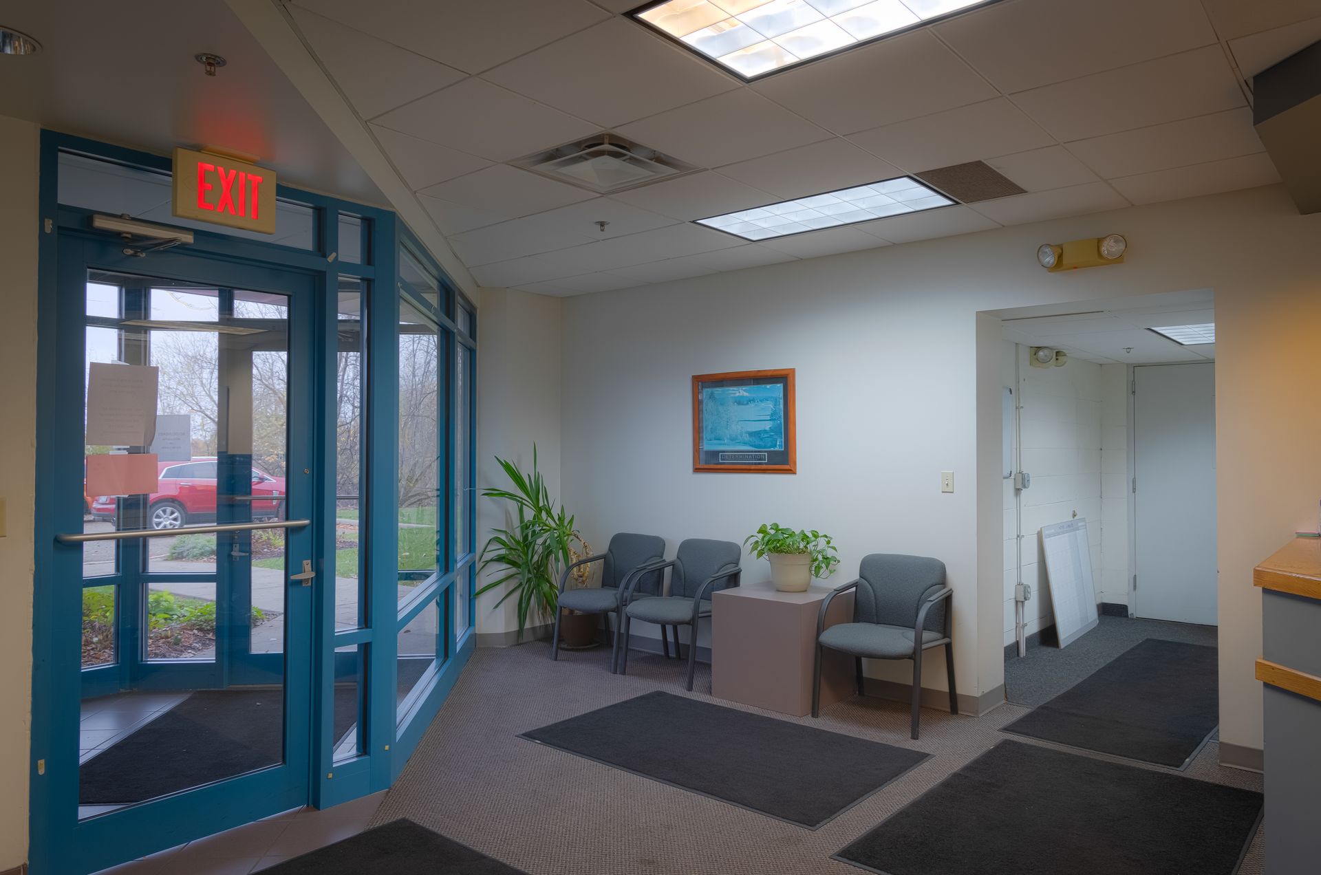 A red exit sign hangs above a blue door