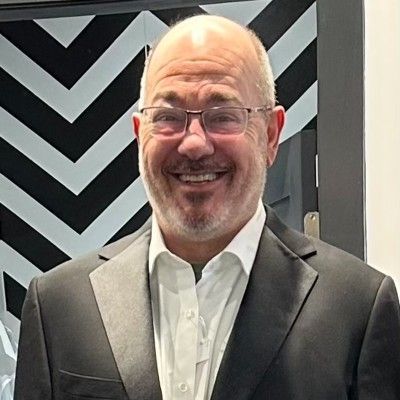 A bald man wearing glasses and a suit is smiling in a circle.