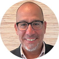 A man in a suit and blue shirt is smiling in a circle.