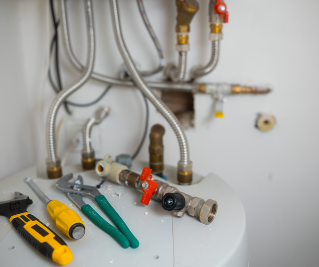 Plumbing tools and pipes arranged near a water heater.