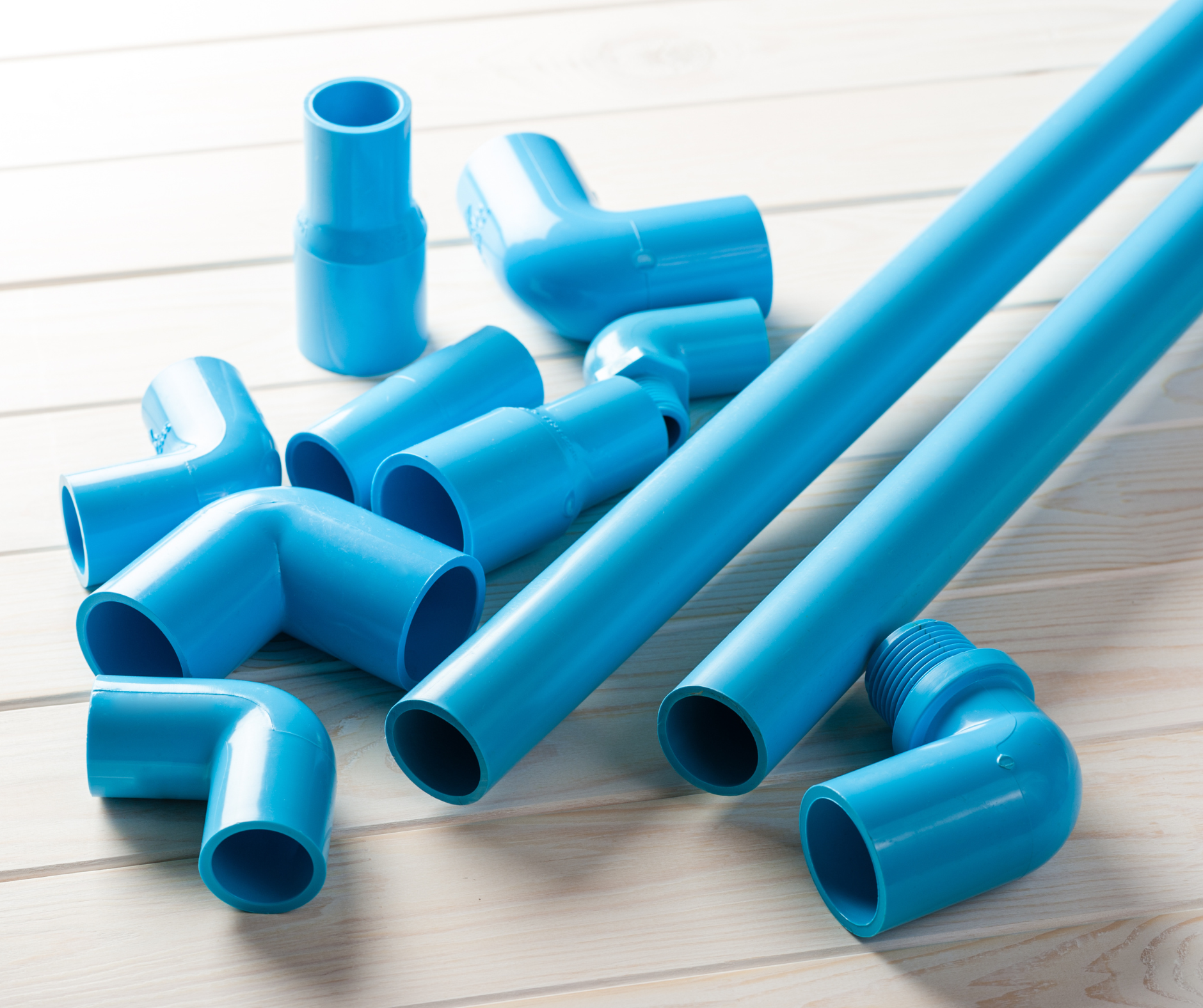 Blue PVC pipes and fittings on a light wood surface.
