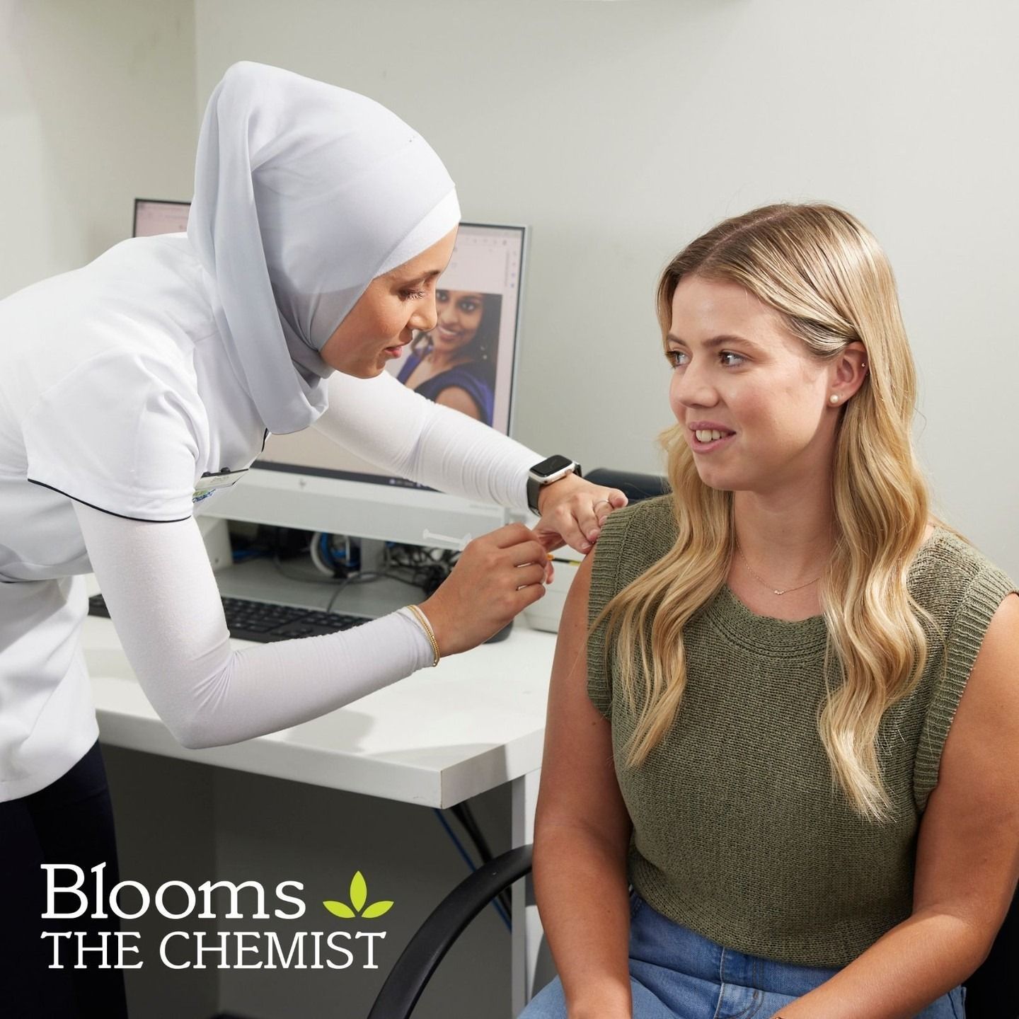 A Woman in a Hijab Administers a Vaccine to a Seated Woman at a Pharmacy — Blooms The Chemist Sawtell in Sawtell, NSW