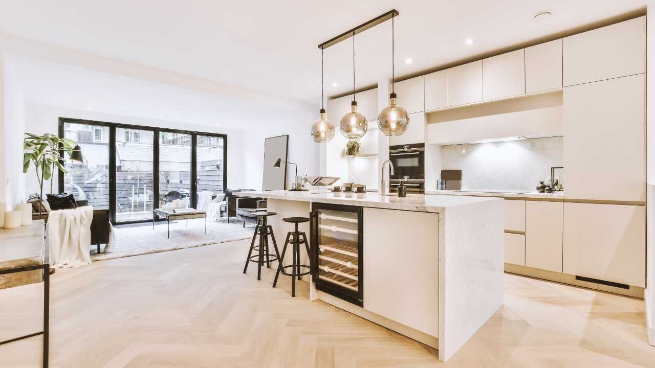 Modern kitchen featuring white cabinets and wooden flooring.