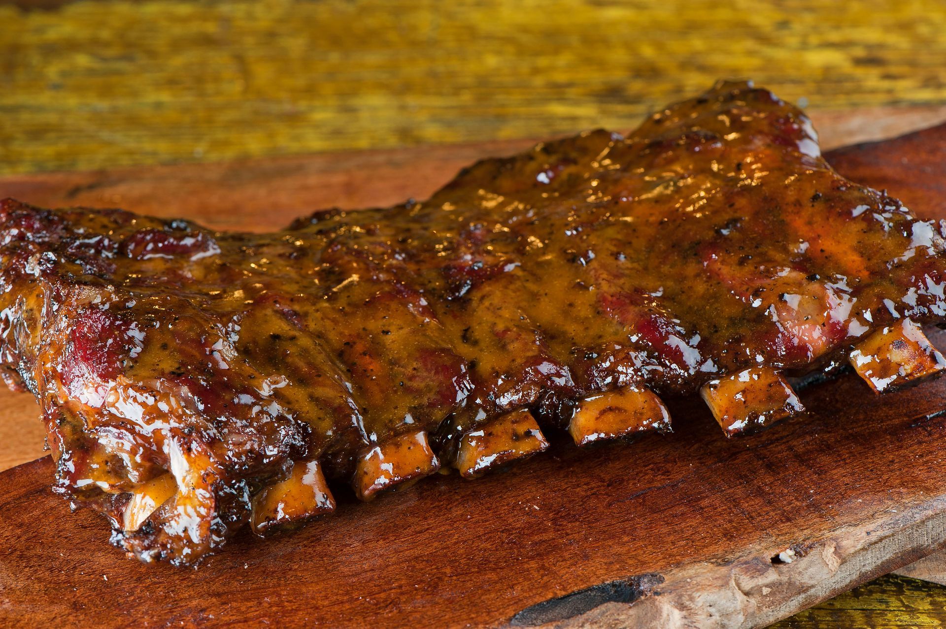 Barbecue ribs glazed with sauce on a wooden cutting board