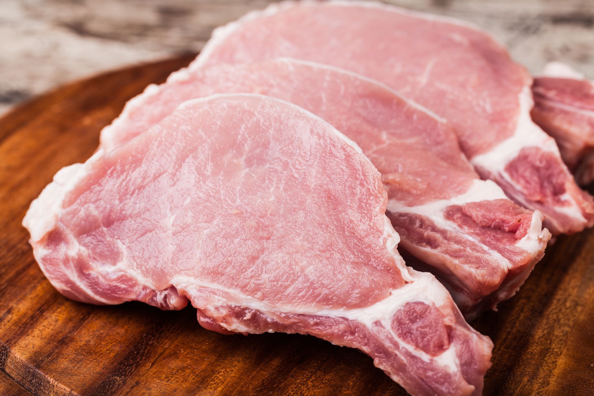 Raw pork chops on a wooden cutting board