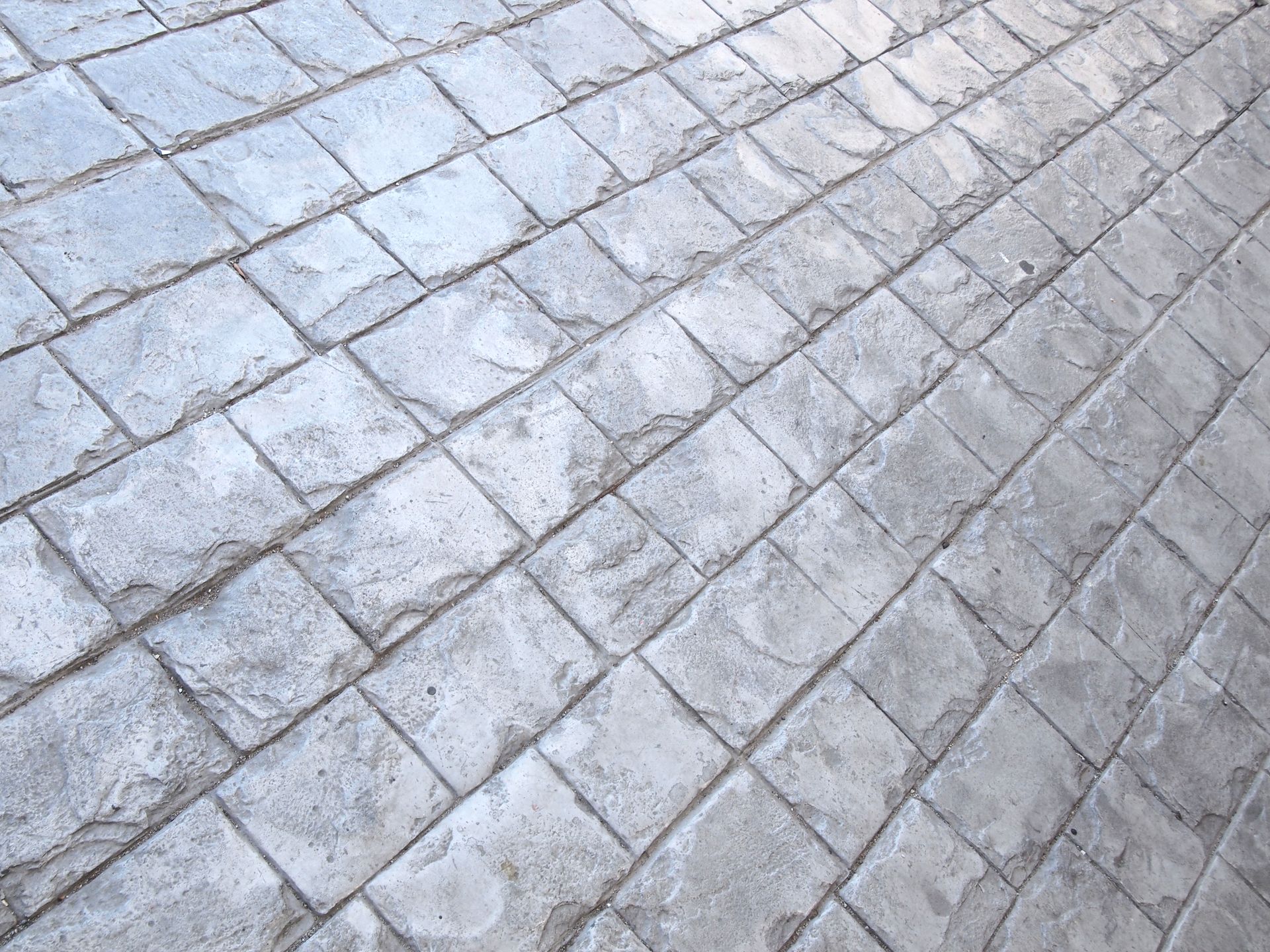 A brick driveway leading to a house with a lush green lawn.