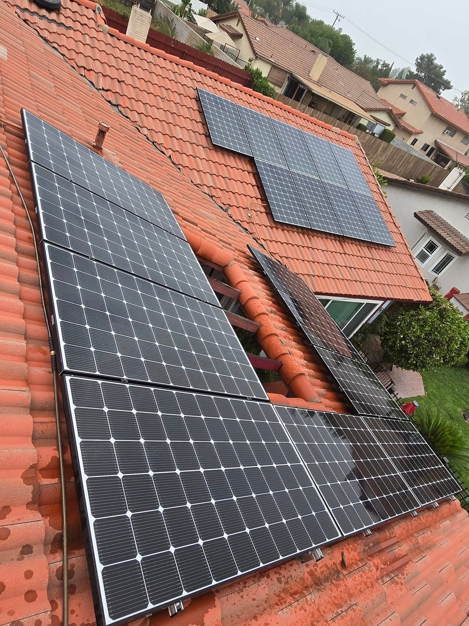 There are many solar panels on the roof of a house.