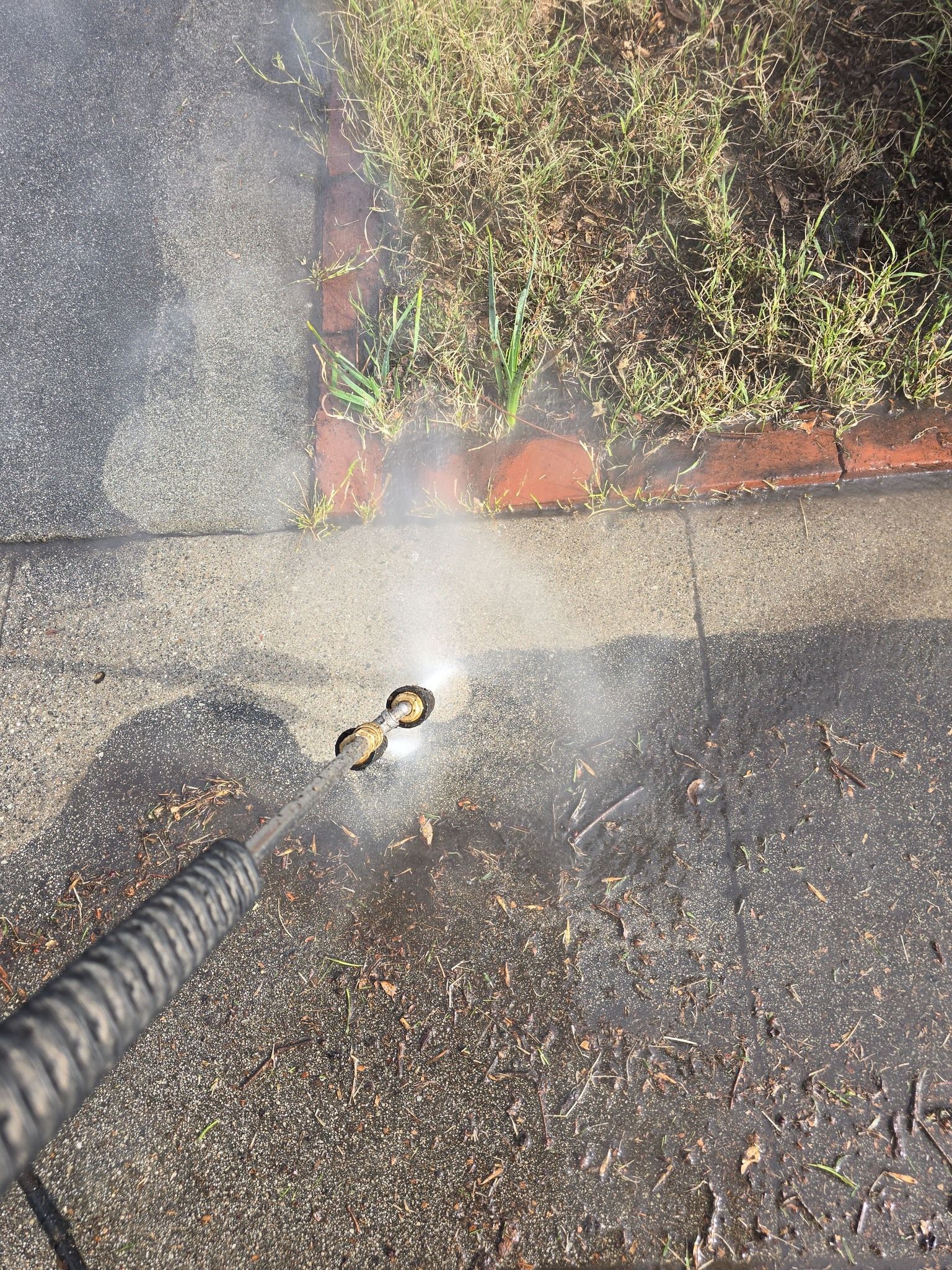 A person is using a pressure washer to clean a sidewalk.