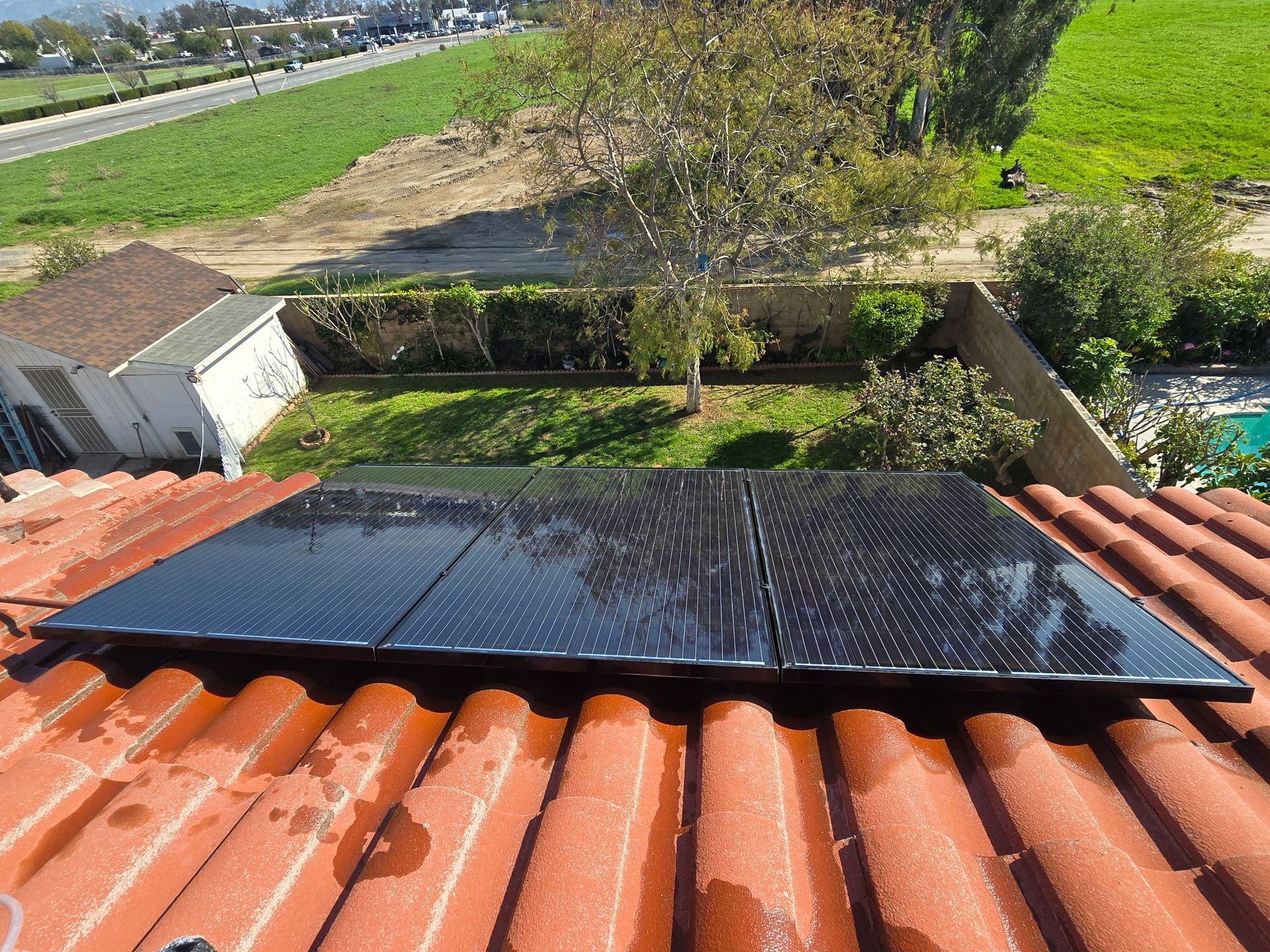 A solar panel is sitting on top of a tiled roof.