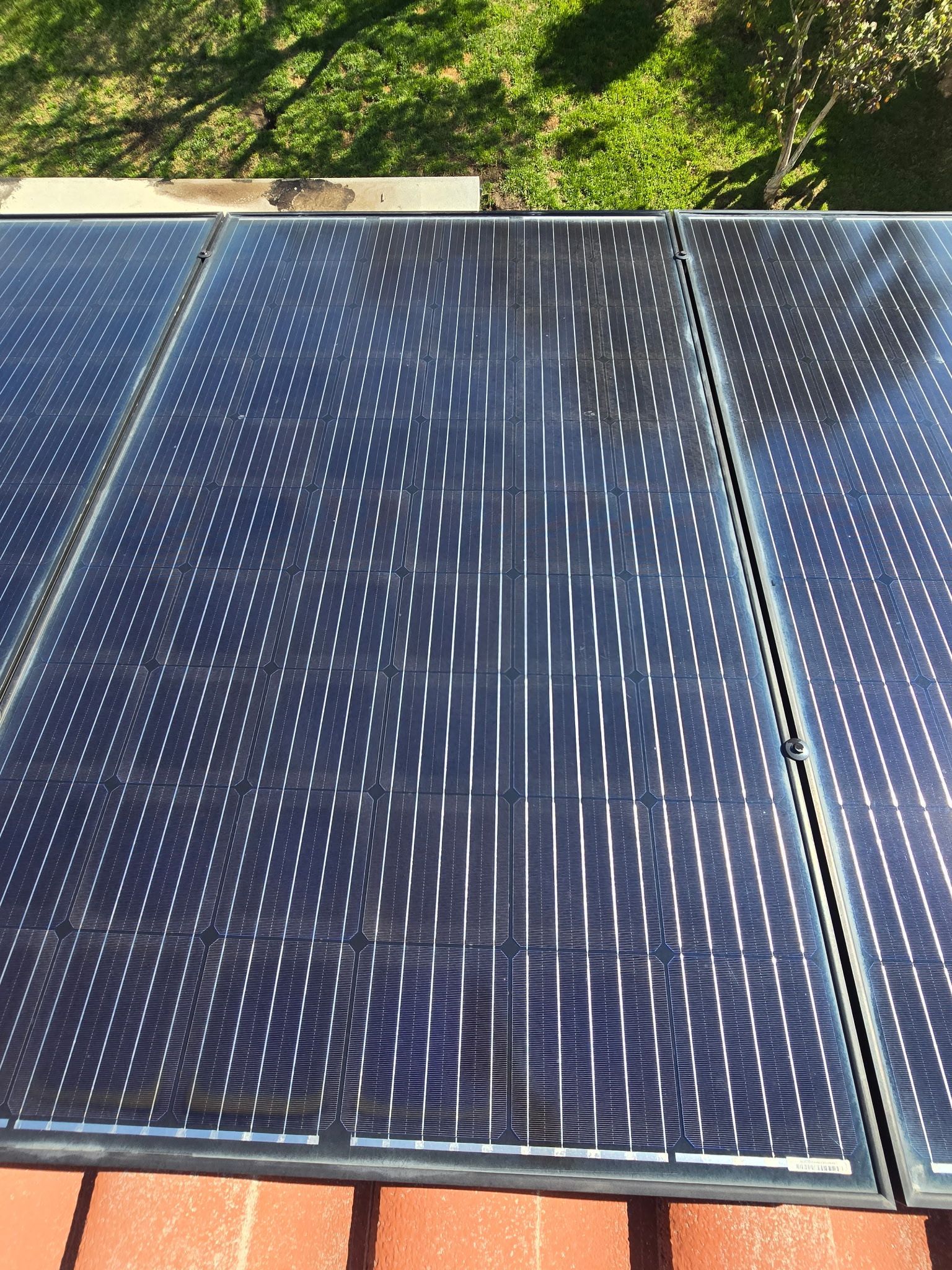 Three solar panels are sitting on top of a brick roof.