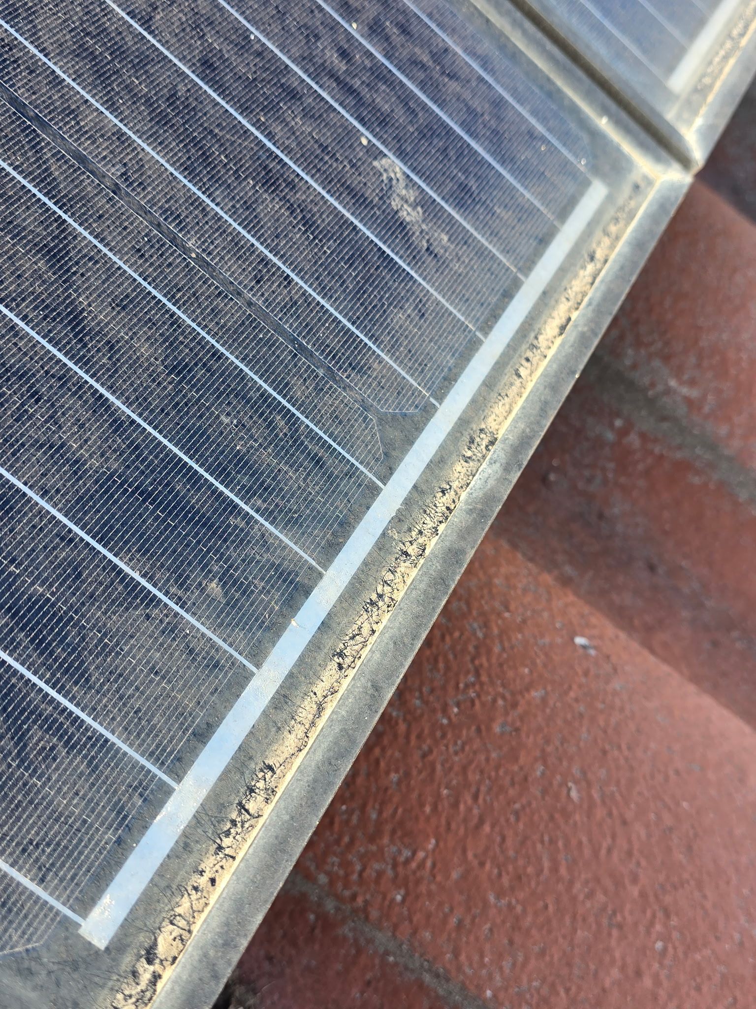 A close up of a solar panel on a brick roof.