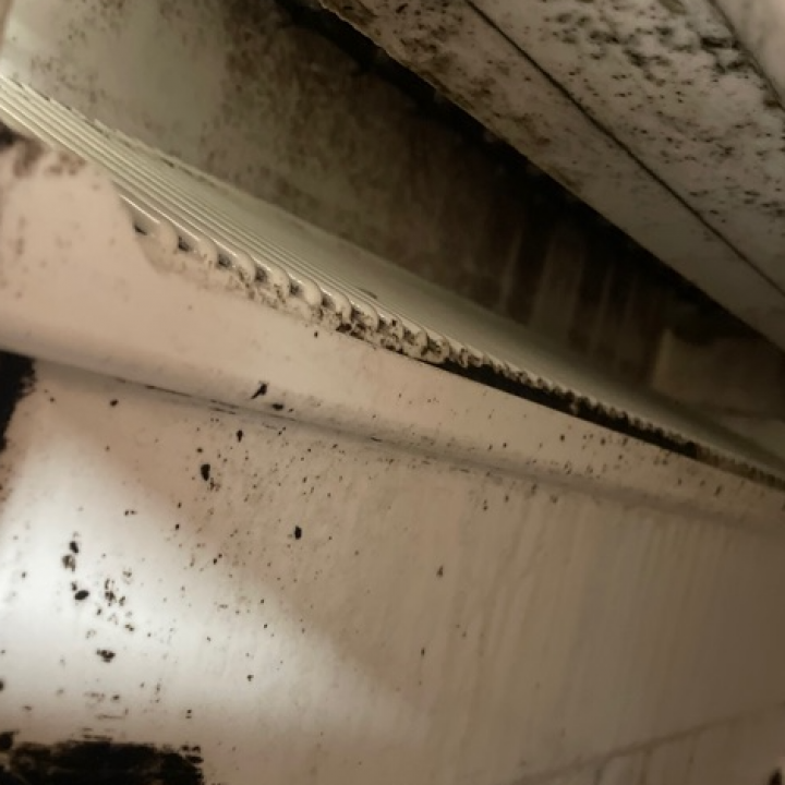 Close-up of a white air vent with black mold and dirt buildup along the edges.