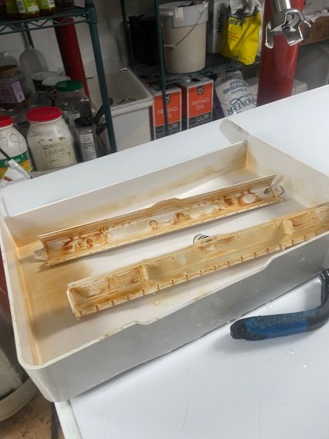 White plastic drip tray with brown stains; a handle rests beside it.