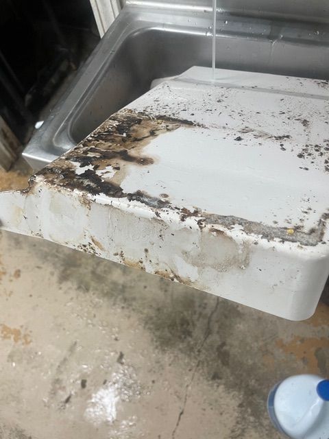 White countertop with heavy staining and damage near a stainless steel sink.