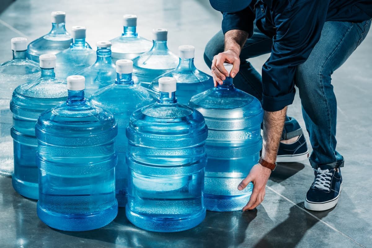 A Man Is Kneeling Down Next to A Pile of Water Bottles — Billabong Springs in Jimboomba, QLD