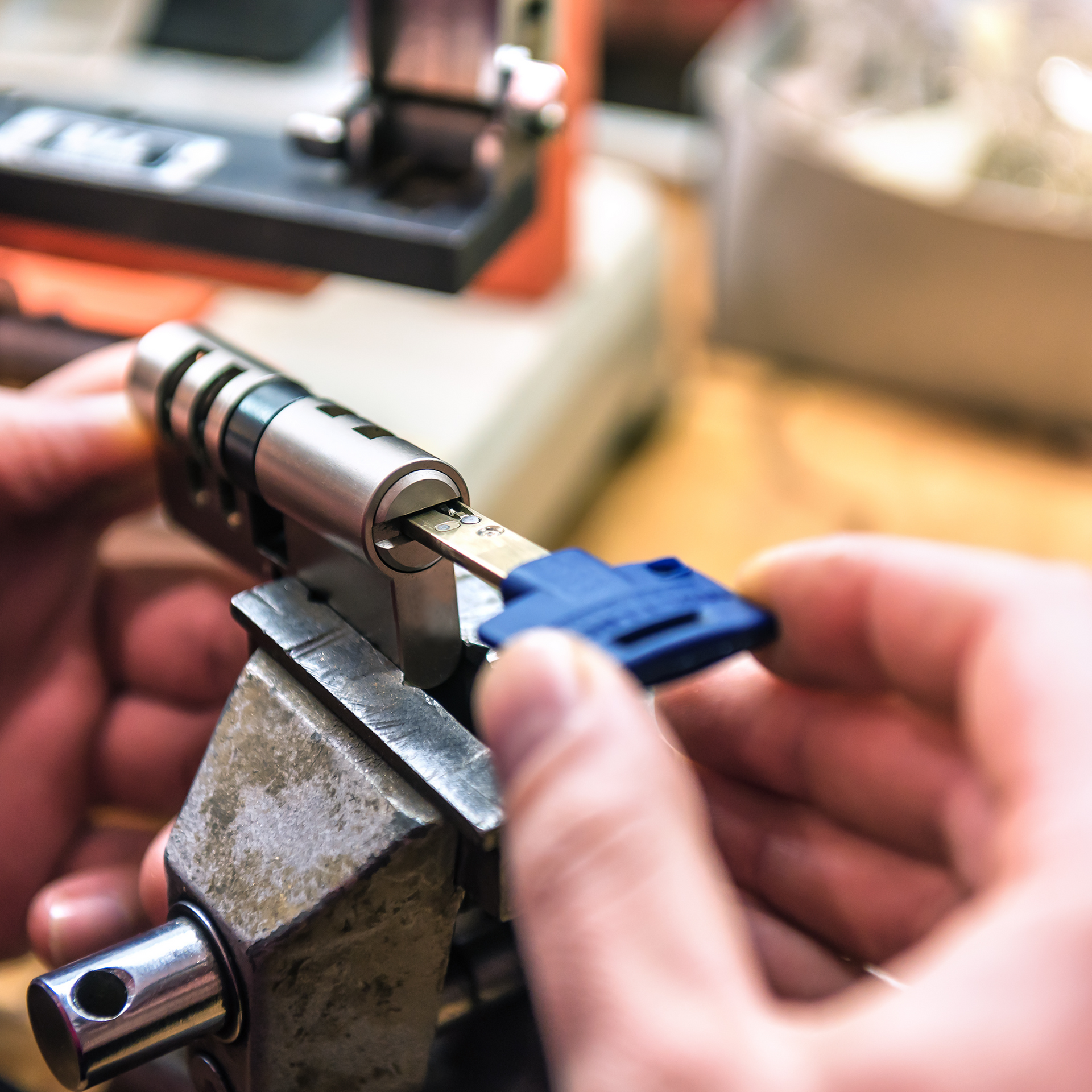 Hands of a locksmith using a key cutting machine to copy a key, close-up shot.