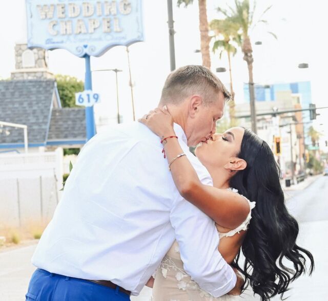 A man and woman kissing in front of a wedding chapel sign