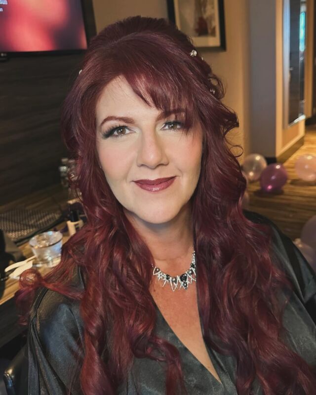 A woman with long red hair is wearing a necklace