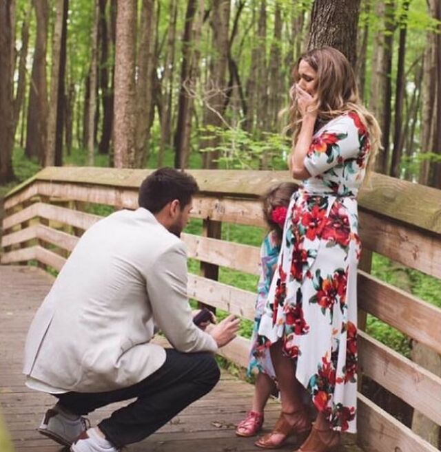 A man is proposing to a woman in a floral dress